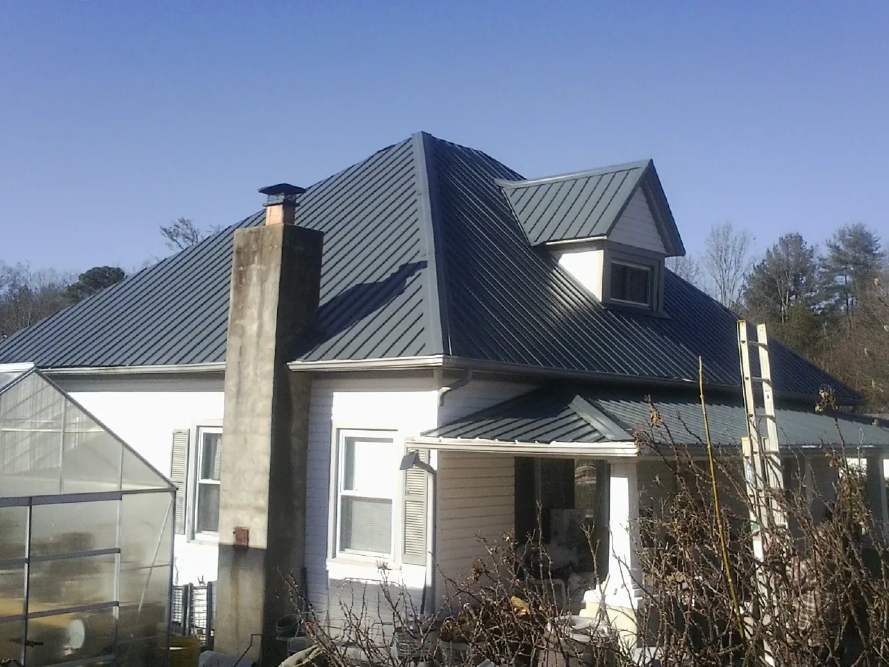 Dark blue standing seam metal roof on a white farmhouse with dormer — Slate & Tile Roof Repair by Roofing Brothers in Mullan