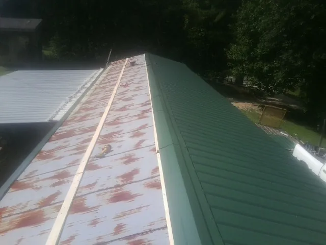 Old rusted panels beside newly installed green metal roofing — Wind Damage Roof Repair by Roofing Brothers in Mullan