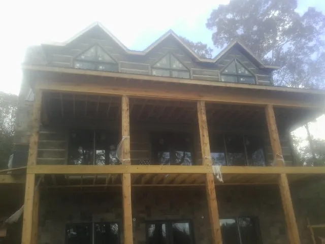 Dormers and porch framing on a large log home under construction — Roof Coating work by our crew in Mullan
