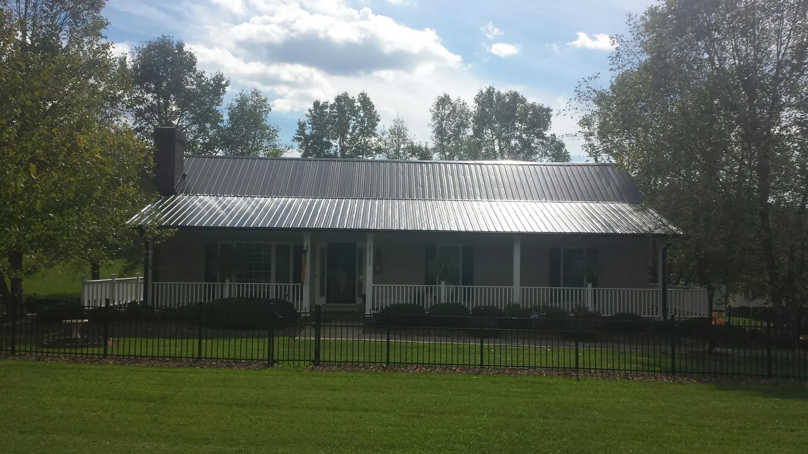 Gray metal roof on a brick ranch with a full width front porch — Gutter Guard Installation work by our crew in Mullan