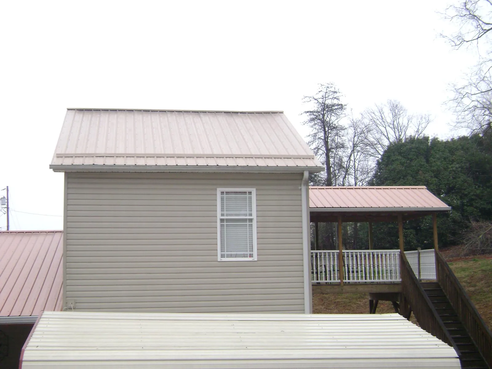 Tan metal roofs on a two story addition and attached porch, from a Roof Replacement job in Mullan
