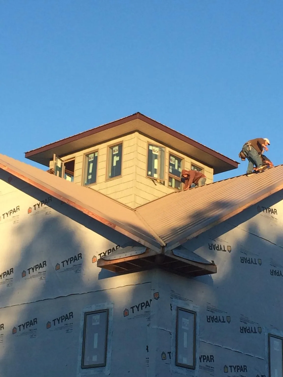 Roofers working around a rooftop cupola on a new metal roof at sunset — Roof Waterproofing in Mullan by Roofing Brothers
